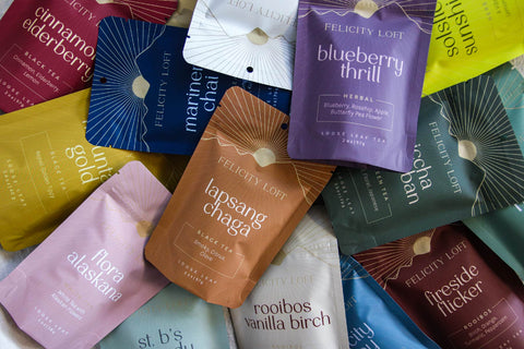 Colorful packages of Felicity Loft tea piled together